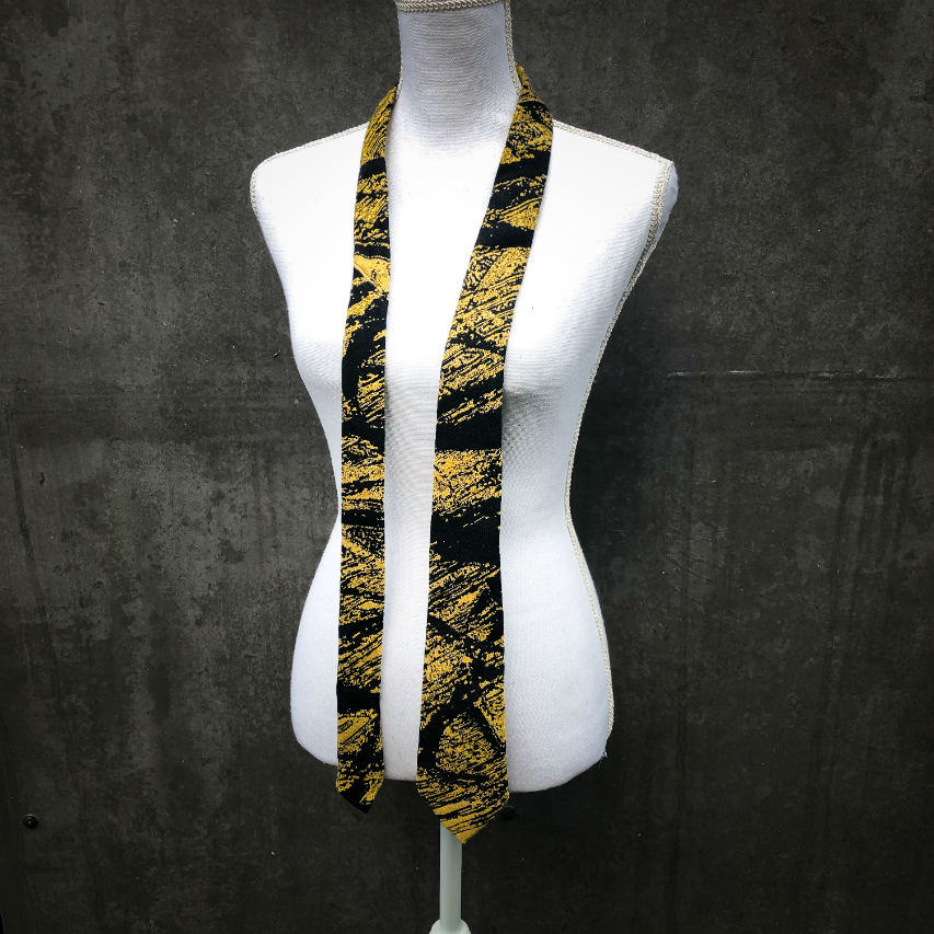 A tie made from black and gold woven wrap, marbled pattern.