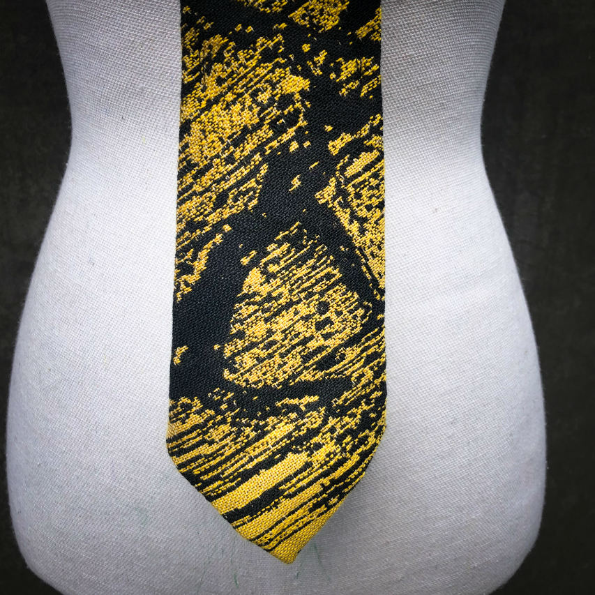 A tie made from black and gold woven wrap, marbled pattern.