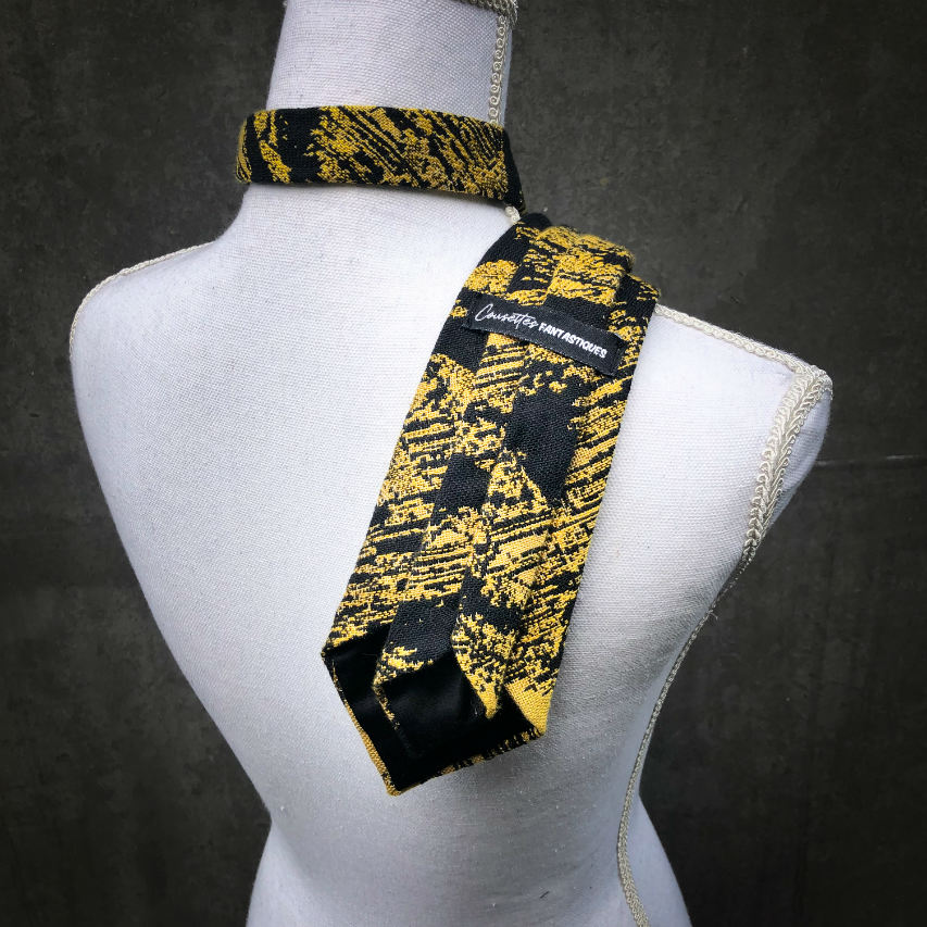 A tie made from black and gold woven wrap, marbled pattern.