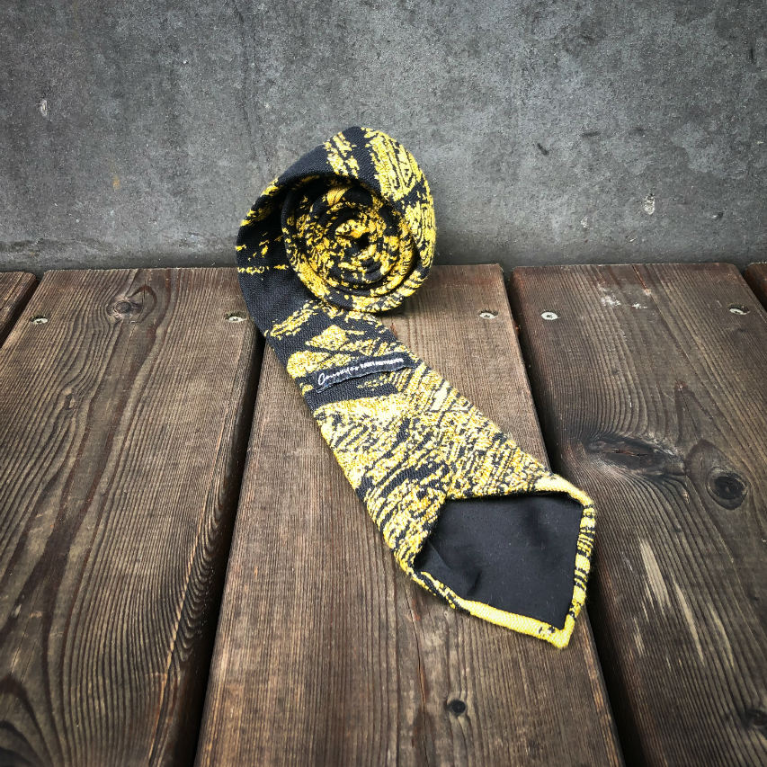 A tie made from black and gold woven wrap, marbled pattern.