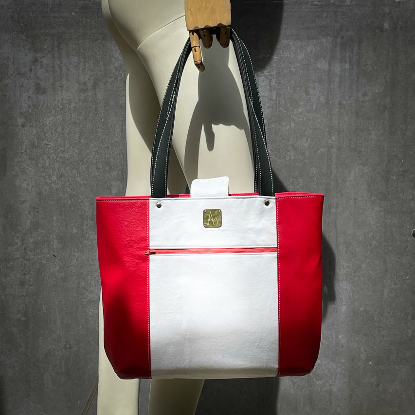 A large bag made from red faux leather on the outside and a canvas printed with a fruit design with an English pun underneath, and on the inside a bright red poplin.