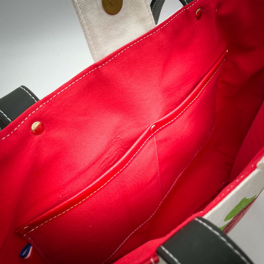 A large bag made from red faux leather on the outside and a canvas printed with a fruit design with an English pun underneath, and on the inside a bright red poplin.