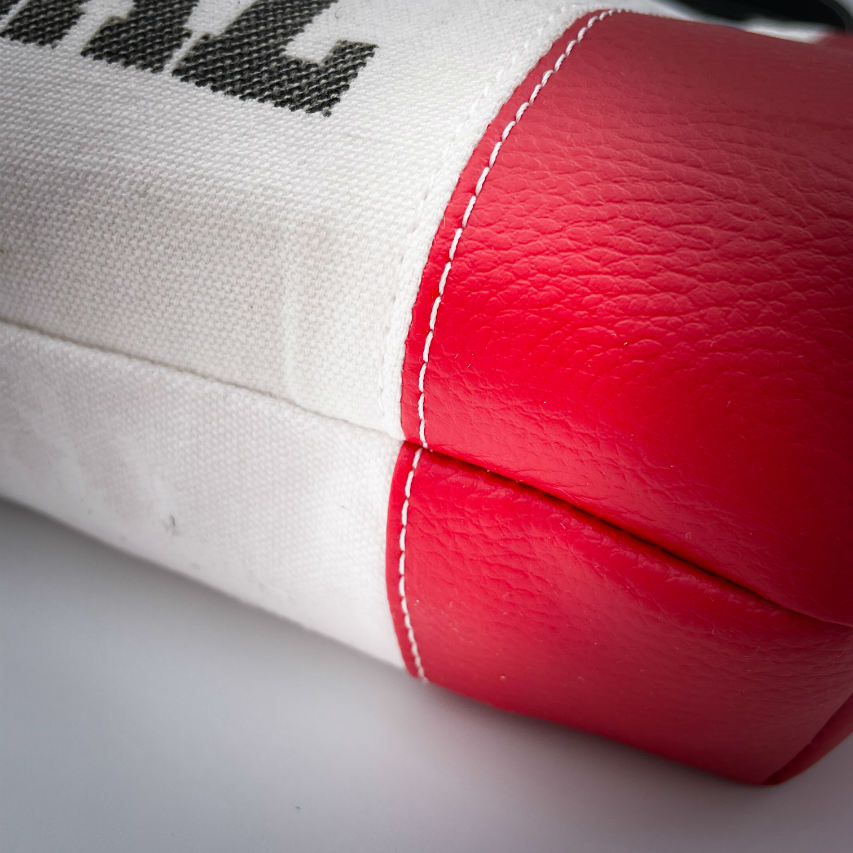 A large bag made from red faux leather on the outside and a canvas printed with a fruit design with an English pun underneath, and on the inside a bright red poplin.