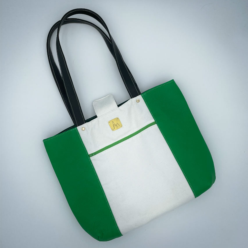 A large bag made from green leather on the outside and a canvas printed with a fruit design with an English pun underneath, and on the inside a forest green poplin.