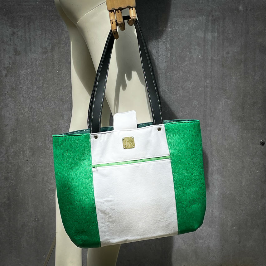 A large bag made from green leather on the outside and a canvas printed with a fruit design with an English pun underneath, and on the inside a forest green poplin.