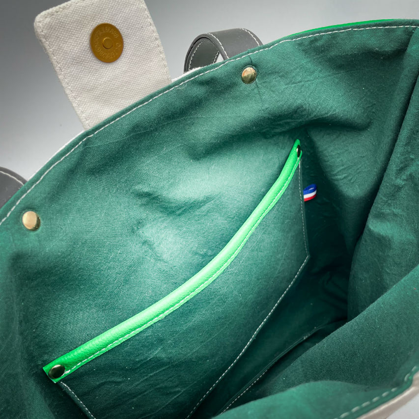 A large bag made from green leather on the outside and a canvas printed with a fruit design with an English pun underneath, and on the inside a forest green poplin.