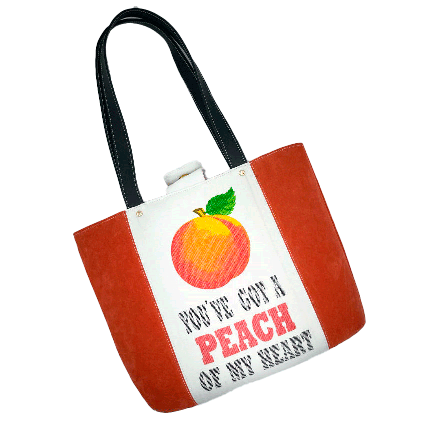 A large bag made from orange leather on the outside and a canvas printed with a fruit design and English wordplay underneath, with an iridescent orange viscose interior.