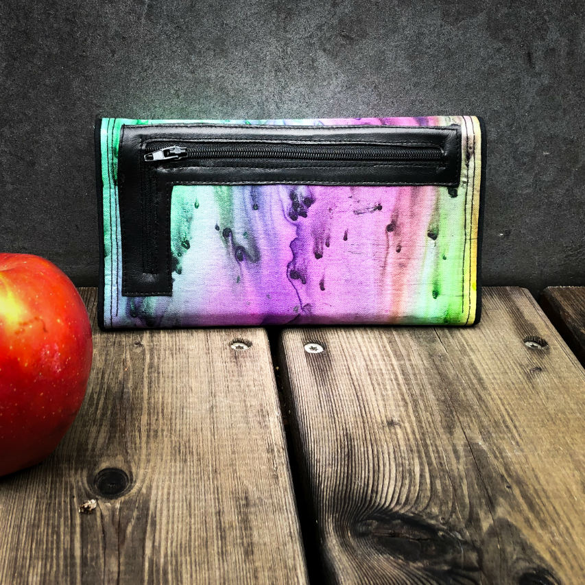 A wallet made from blue, green, and purple pure silk combined with black lambskin on the outside and taupe poplin on the inside.