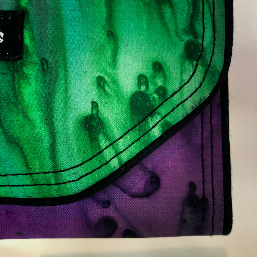 A wallet made from blue, green, and purple pure silk combined with black lambskin on the outside and taupe poplin on the inside.