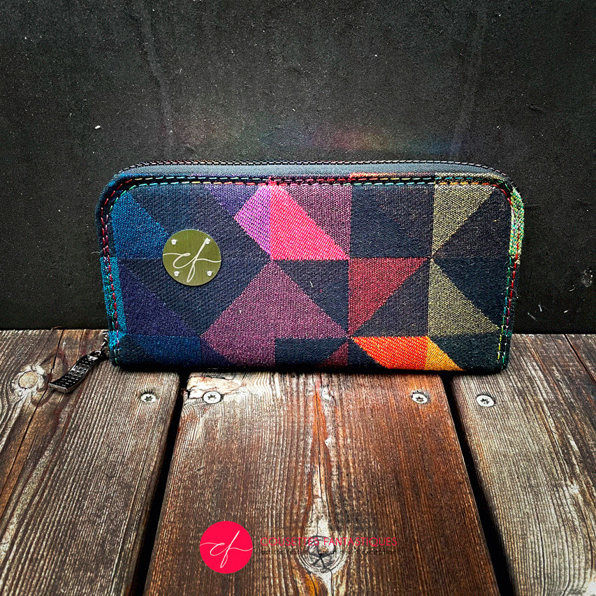 A zippered card and coin holder made from a black and rainbow babywearing wrap with a geometric pattern, royal blue poplin interior.