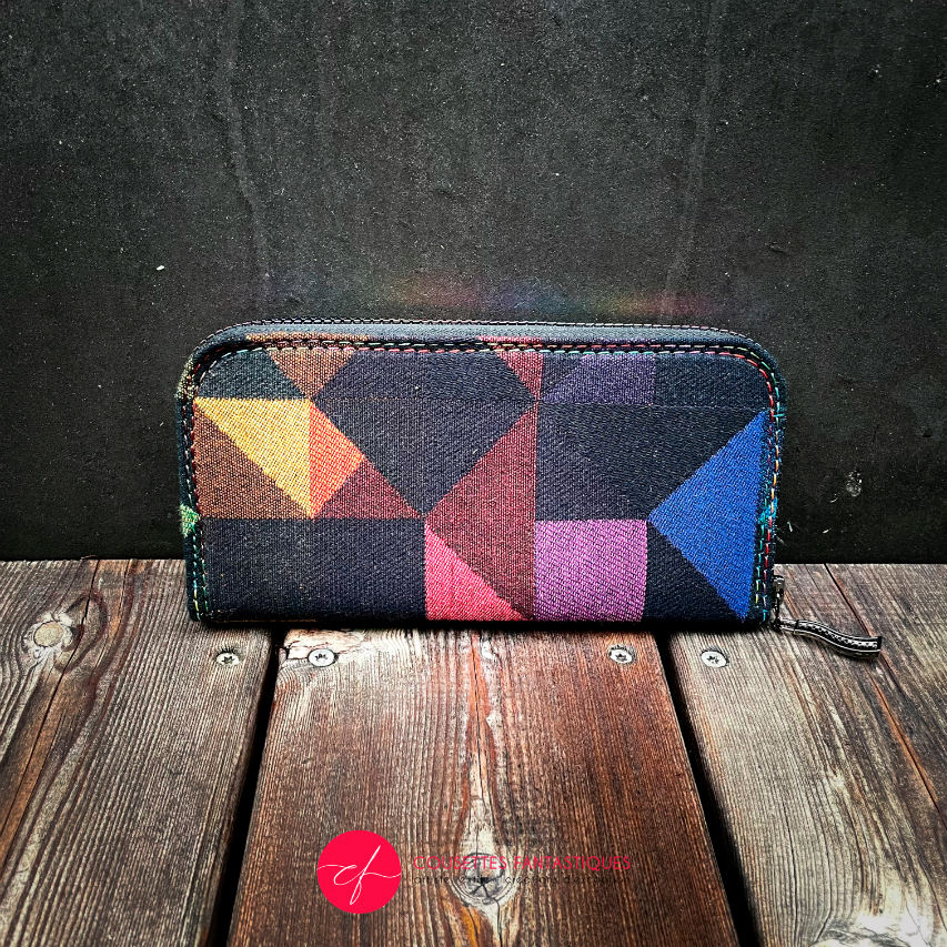 A zippered card and coin holder made from a black and rainbow babywearing wrap with a geometric pattern, royal blue poplin interior.