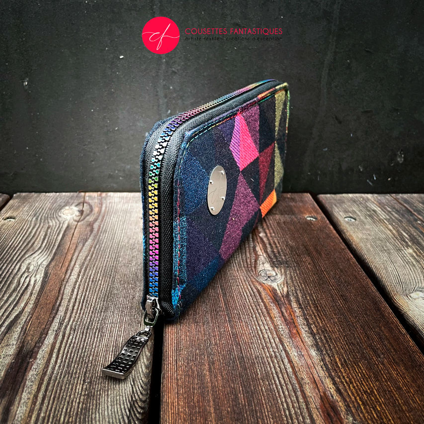 A zippered card and coin holder made from a black and rainbow babywearing wrap with a geometric pattern, royal blue poplin interior.