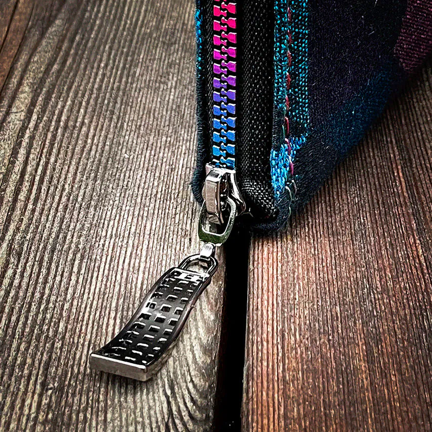 A zippered card and coin holder made from a black and rainbow babywearing wrap with a geometric pattern, royal blue poplin interior.