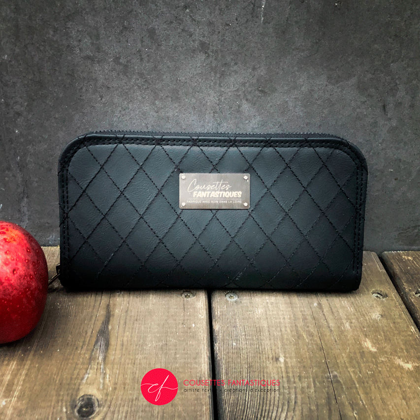 A zippered card and coin holder made with hand-quilted black faux leather on the outside, and cotton canvas with sequins on the inside.