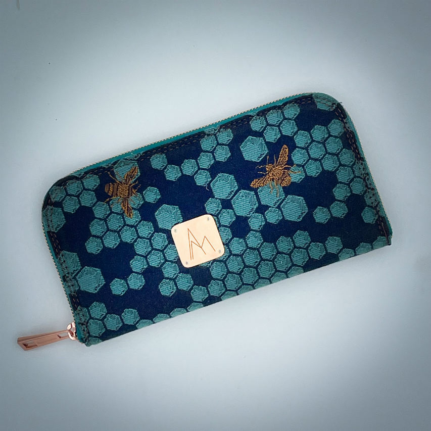 A zippered card and coin holder made with dark blue and petrol blue honeycomb patterned babywearing wrap fabric with bees.