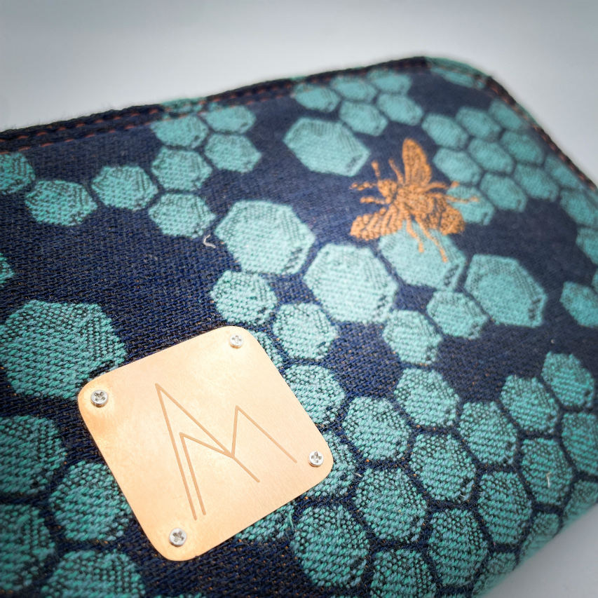 A zippered card and coin holder made with dark blue and petrol blue honeycomb patterned babywearing wrap fabric with bees.