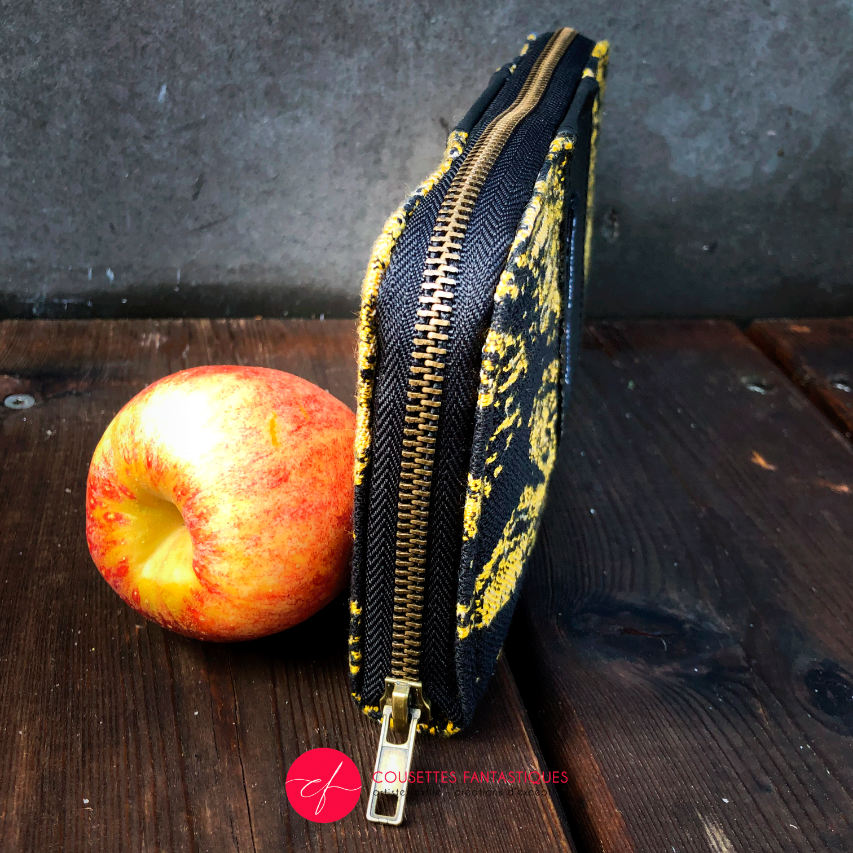 A zippered card and coin holder made with black and gold marbled babywearing wrap fabric and matte black cork.