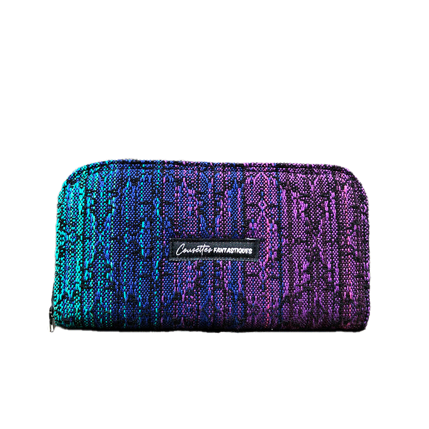 A wallet made with a babywearing wrap in a gradient from blue to violet on the outside and black, pink, and petrol poplin on the inside.