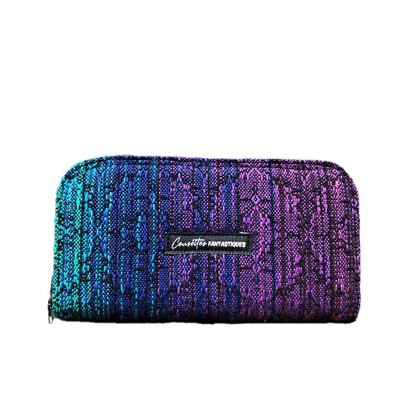 A wallet made with a babywearing wrap in a gradient from blue to violet on the outside and black, pink, and petrol poplin on the inside.
