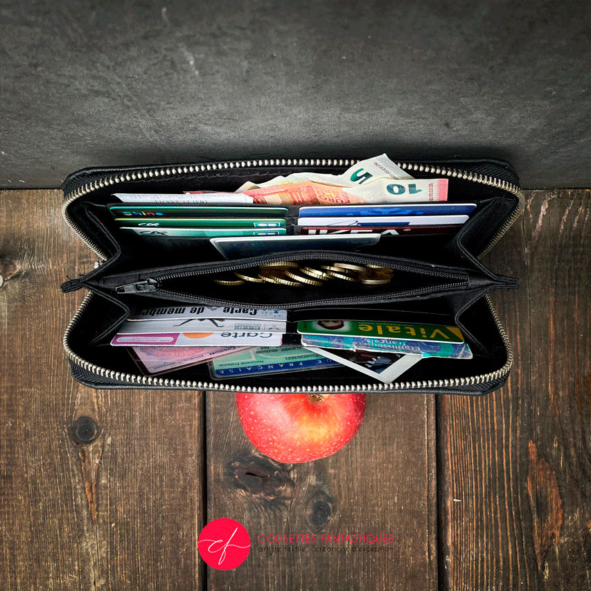 A wallet made with a babywearing wrap in a gradient from blue to violet on the outside and black, pink, and petrol poplin on the inside.