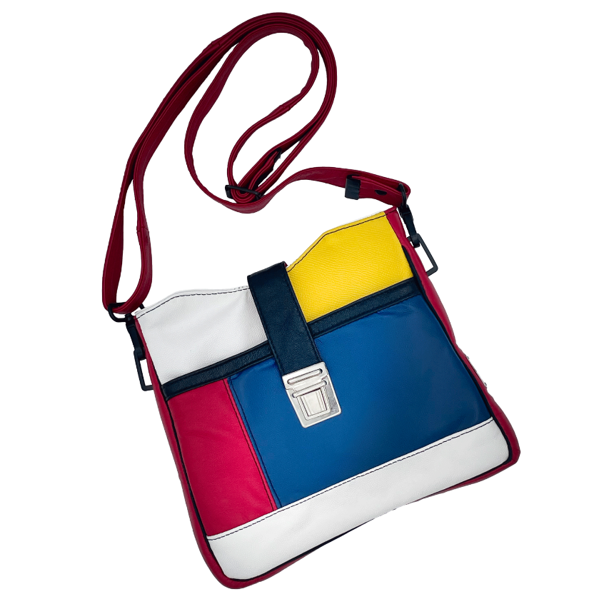 Un sac besace composé de différents cuirs bleu roi, rouge profond, jaune vif, blanc et noir.