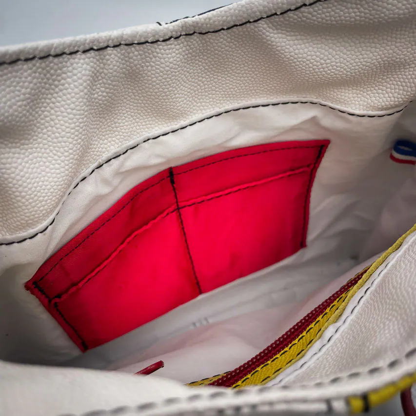 Un sac besace composé de différents cuirs bleu roi, rouge profond, jaune vif, blanc et noir.
