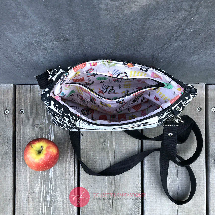 Un sac en bandoulière trapézoïdal fabriqué à partir de toile en coton noir et blanc avec des motifs stylisés de chats et d'oiseaux, assorti à de la cretonne de coton à thème aviaire à l'intérieur.