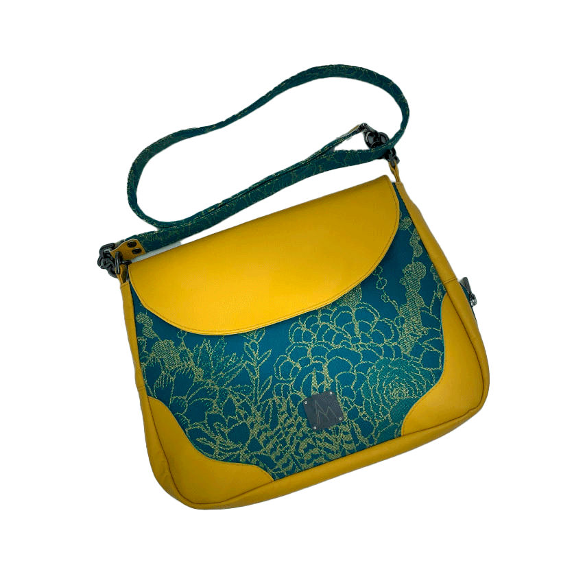 Un sac besace confectionné à partir d'écharpe de portage au motif de succulentes jaunes sur fond turquoise et d'un cuir jaune soleil, couplés à deux popelines bleu glace et jaune à l'intérieur.