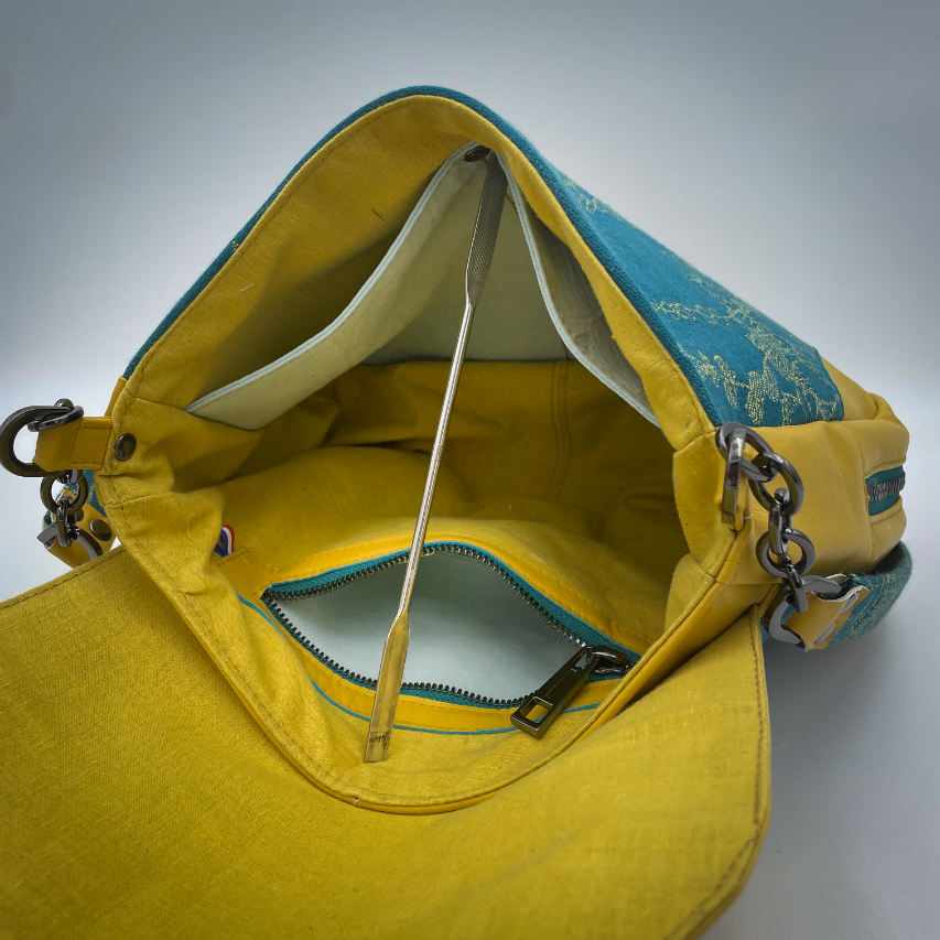 Un sac besace confectionné à partir d'écharpe de portage au motif de succulentes jaunes sur fond turquoise et d'un cuir jaune soleil, couplés à deux popelines bleu glace et jaune à l'intérieur.