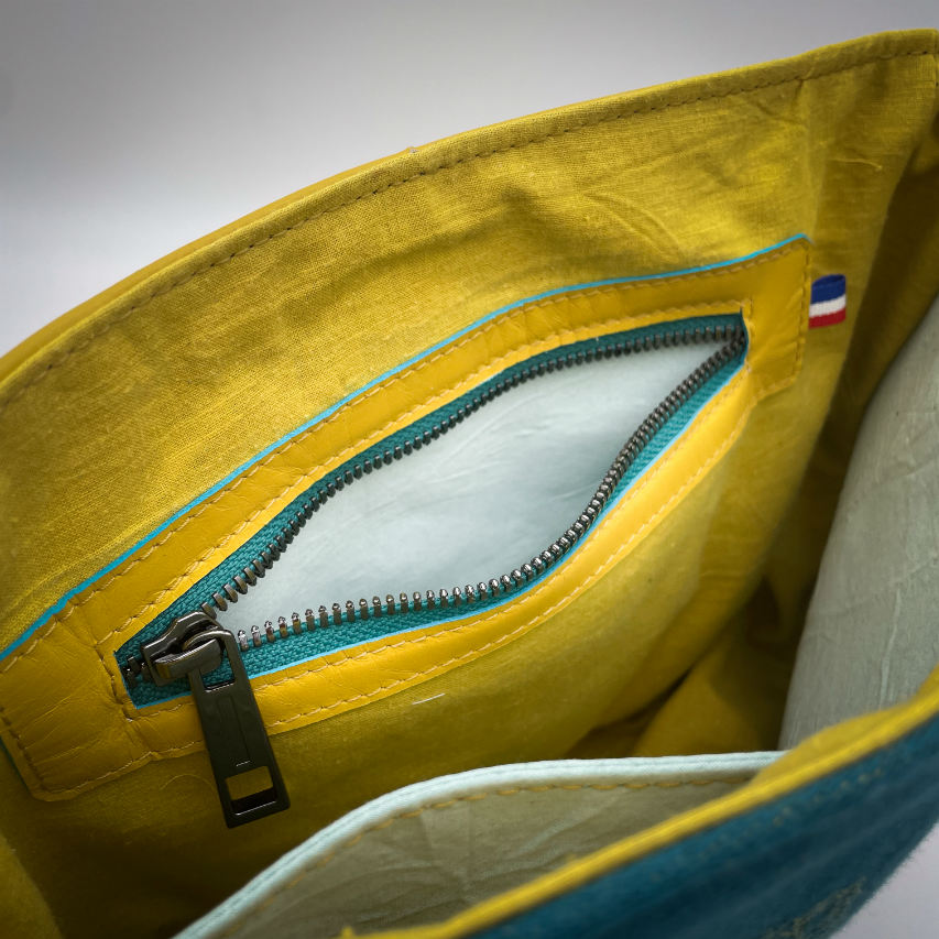 Un sac besace confectionné à partir d'écharpe de portage au motif de succulentes jaunes sur fond turquoise et d'un cuir jaune soleil, couplés à deux popelines bleu glace et jaune à l'intérieur.