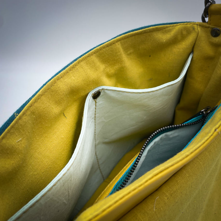 Un sac besace confectionné à partir d'écharpe de portage au motif de succulentes jaunes sur fond turquoise et d'un cuir jaune soleil, couplés à deux popelines bleu glace et jaune à l'intérieur.