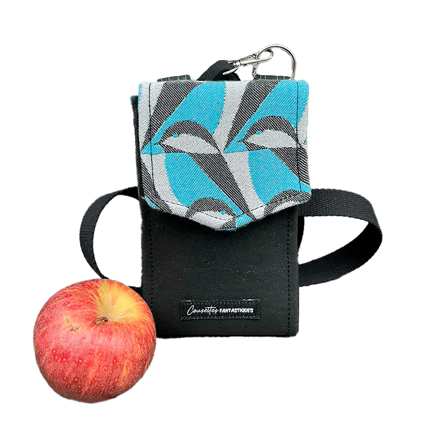 Un portefeuille-sac fabriqué à partir d'une écharpe de portage grise, noir et bleu ciel avec des motifs stylisés de tête de moineau, et du liège noir.