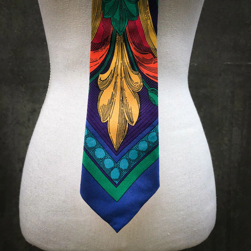 Une cravate fabriquée à partir d'un foulard de soie rouge, bleu, vert, jaune... et au motif rococco.