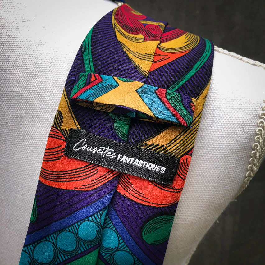 Une cravate fabriquée à partir d'un foulard de soie rouge, bleu, vert, jaune... et au motif rococco.