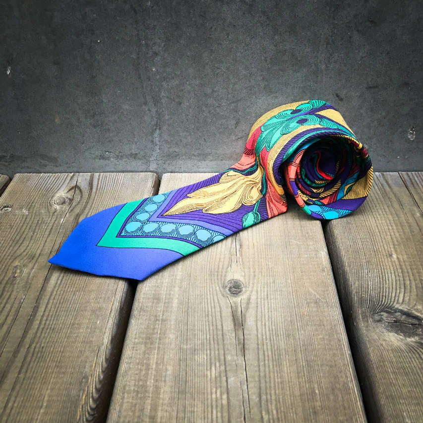 Une cravate fabriquée à partir d'un foulard de soie rouge, bleu, vert, jaune... et au motif rococco.