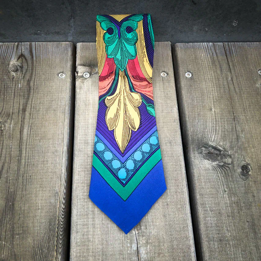 Une cravate fabriquée à partir d'un foulard de soie rouge, bleu, vert, jaune... et au motif rococco.