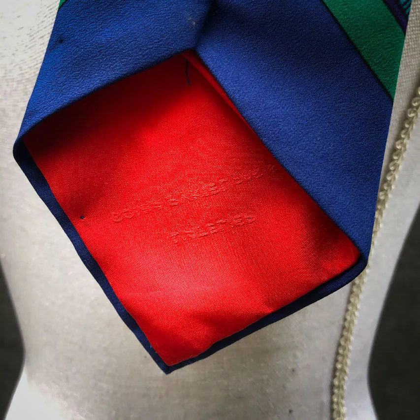 Une cravate fabriquée à partir d'un foulard de soie rouge, bleu, vert, jaune... et au motif rococco.