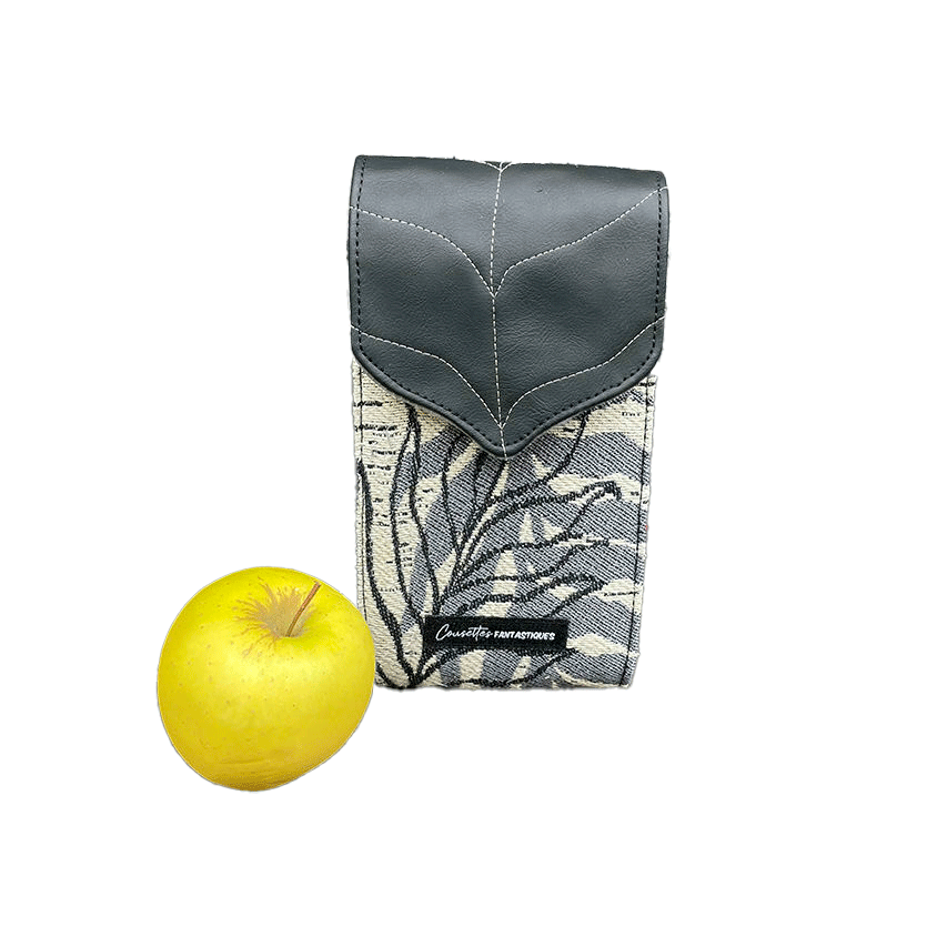 Un compagnon fabriqué à partir d'une écharpe de portage blanche, noire et grise avec des motifs de feuilles tropicales et un simili cuir noir.
