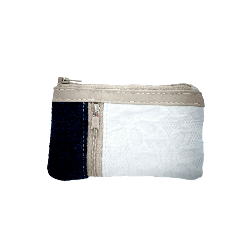 Un petit porte-monnaie zippé fabriqué à partir d'un pull en laine bleu marine, d'un tissu damassé blanc et d'un simili suédé beige.