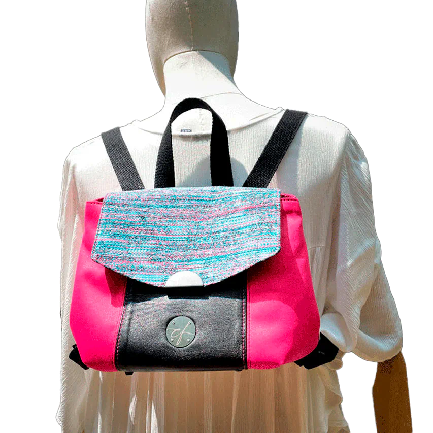 Un sac à dos fabriqué avec un tissu d'ameublement rose vif, du cuir noir et un coupon d'écharpe de portage au motif floral.
