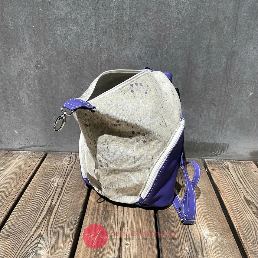 Un sac à dos confectionné en neoprene violet et en tissu d'écharpe dans des tons écru et violet, au motif d'oiseaux dans des branches.
