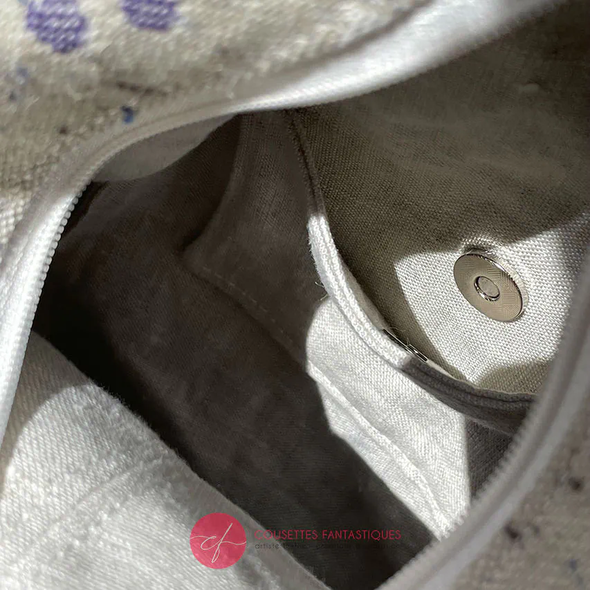 Un sac à dos confectionné en neoprene violet et en tissu d'écharpe dans des tons écru et violet, au motif d'oiseaux dans des branches.