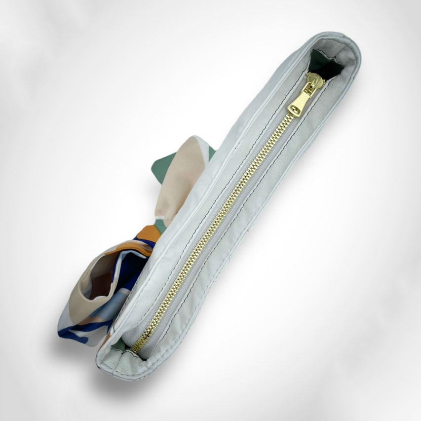 Une petite pochette zippée cousue en similicuir blanc et une écharpe colorée avec un design floral moderne et abstrait en blanc, bleu, sauge, beige et cannelle. À l'intérieur se trouve un popeline brillant de couleur sauge claire.