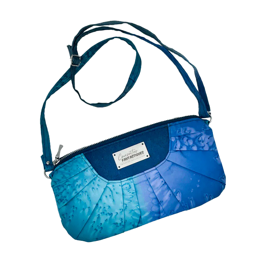 Une pochette zippée cousue dans un foulard en soie dans les tons bleus, plissé et associé à du liège bleur roi.