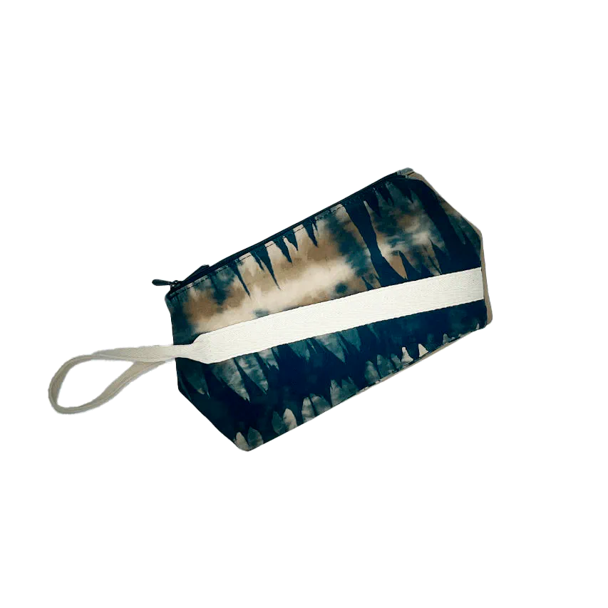 Une pochette zippée double cousue dans une suédine synthétique beige et un tissu au motif abstrait dans les tons vert forêt, beige et fauve, doublé d'une popeline vert amande.