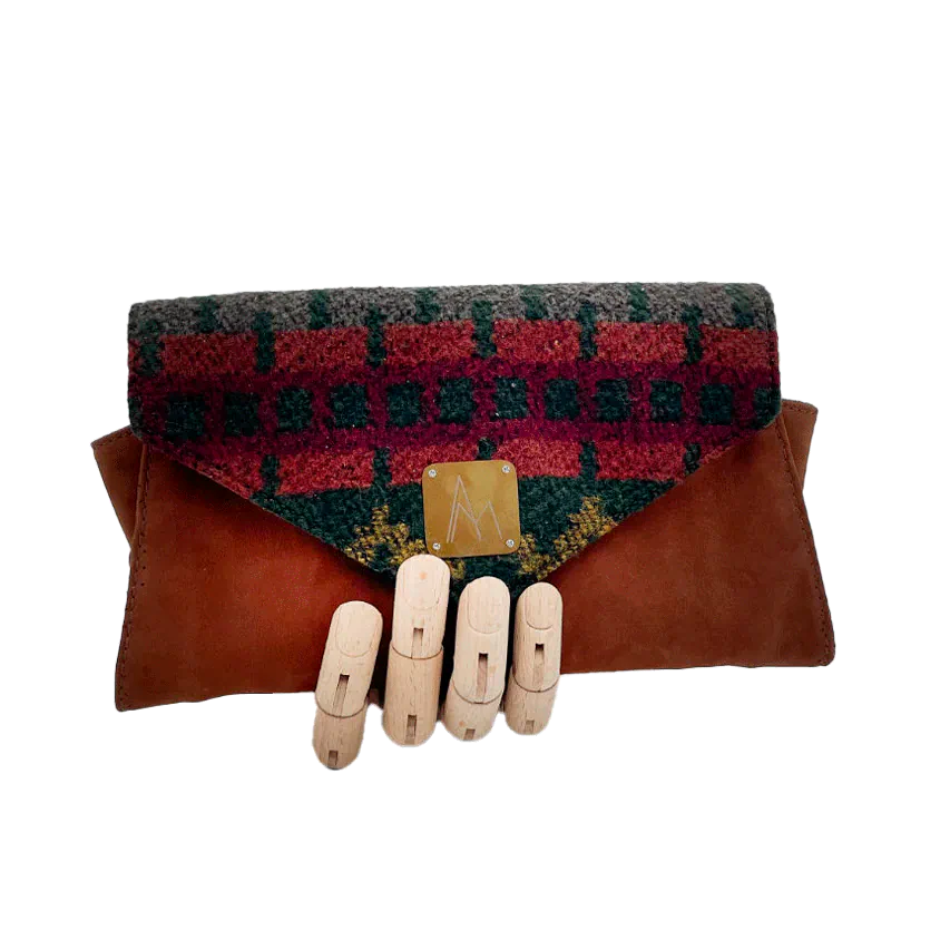 Un portefeuille fabriqué à partir de en suédine alezan et drap laine au motif géométrique, avec une doublure en viscose à motif géométrique.