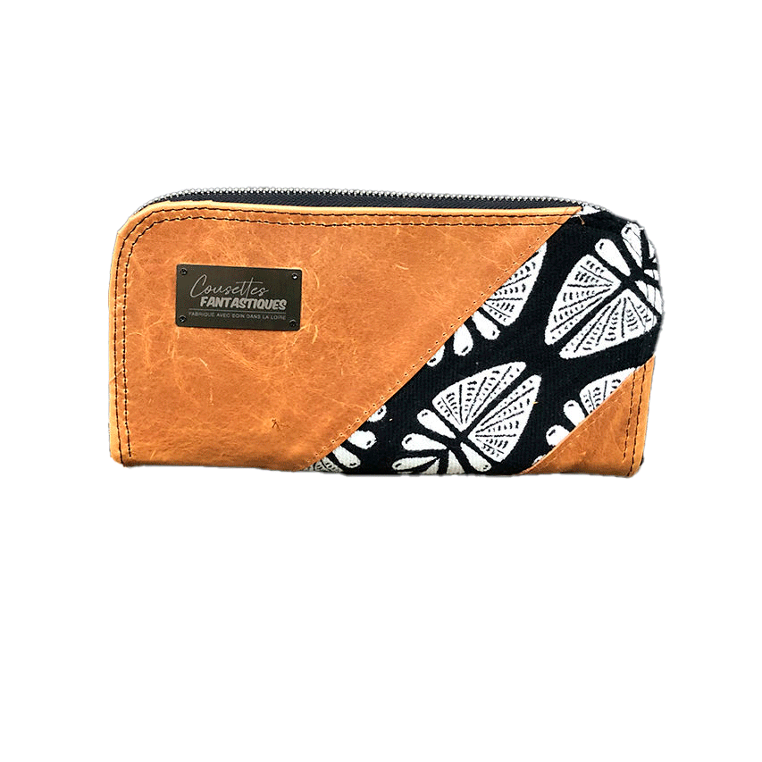 Un portefeuille fabriqué à partir de cuir caramel et d'un coupon d'écharpe de portage en noir et blanc au motif géométrique inspiré par la nature à l'extérieur, et de popeline noire à l'intérieur.