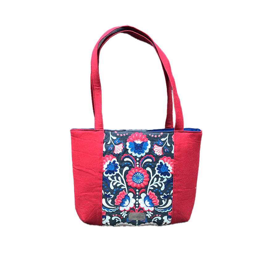 Un sac cabas en tissu gris brodé de motifs floraux scandinaves bleus, rouges et blancs, en gabardine rouge et en popeline bleu roi.