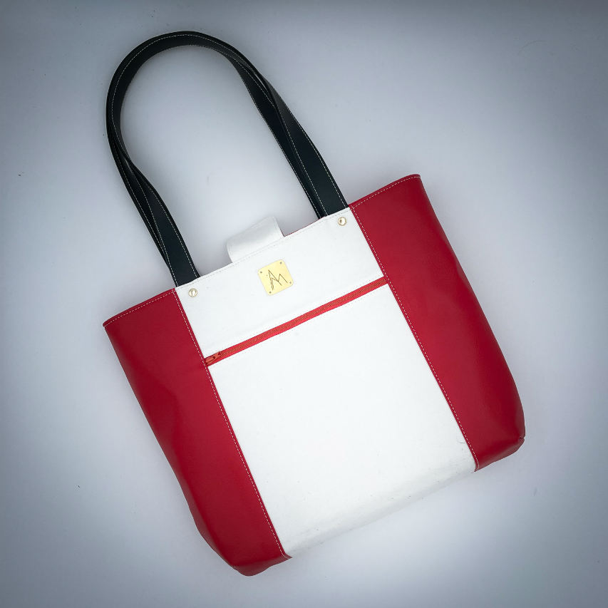 Un grand sac fait à l'extérieur de simili rouge et d'une toile imprimée d'un dessin de fruit avec un jeu de mots en anglais dessous, et à l'intérieur d'une popeline rouge vif.