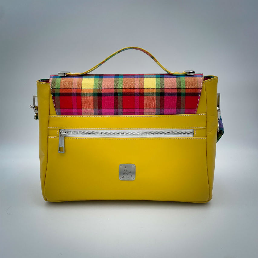 Un sac cartable constitué de cuir jaune et de toile de madras multicolore.